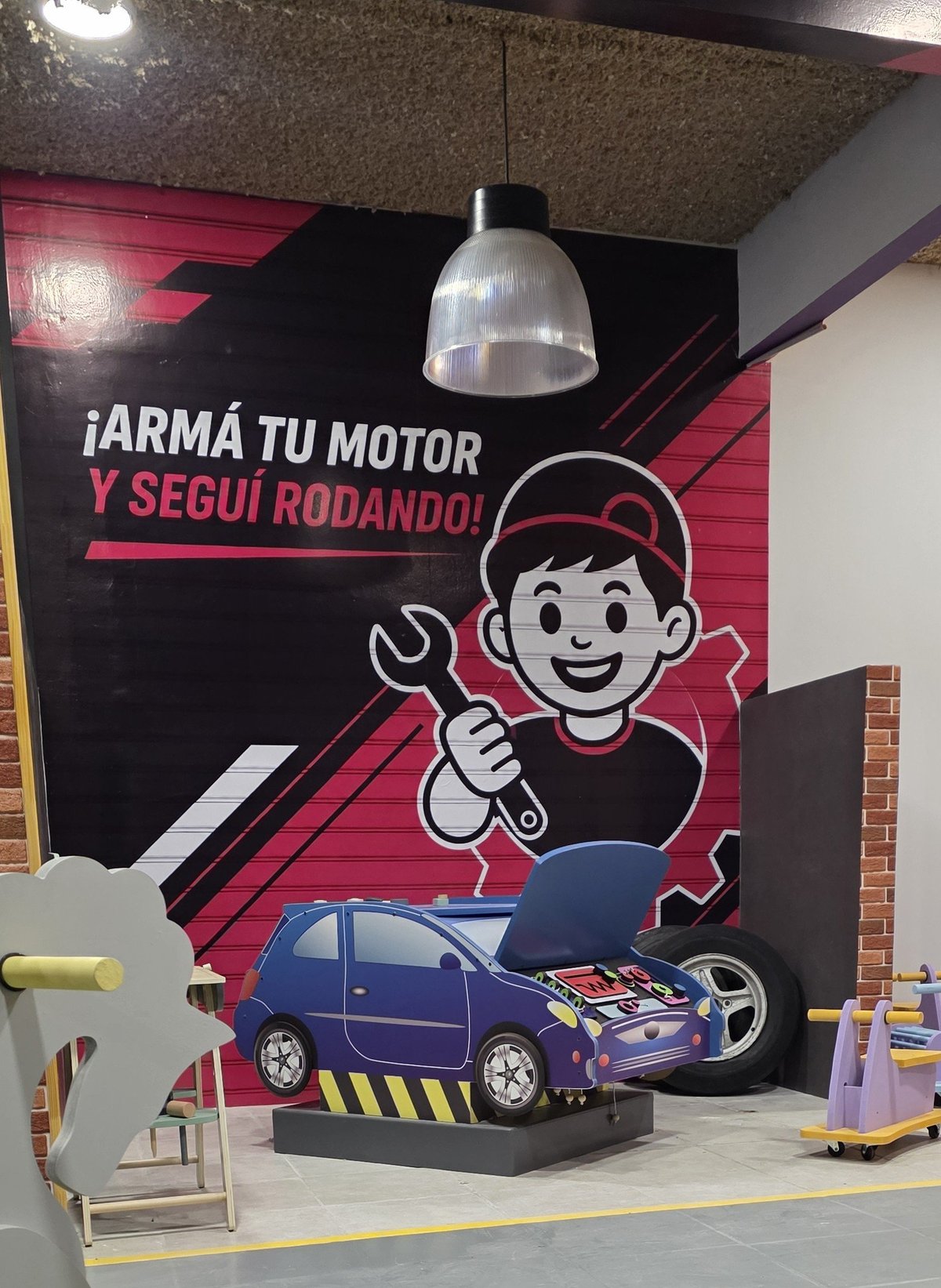 Mural del taller mecánico con personaje y autito azul bajo lámpara